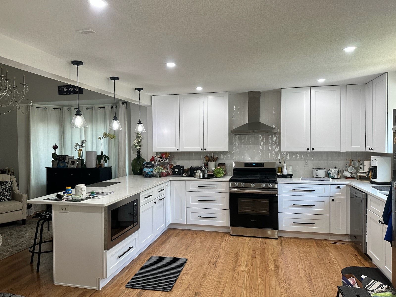 A kitchen with white cabinets , stainless steel appliances , and hardwood floors.