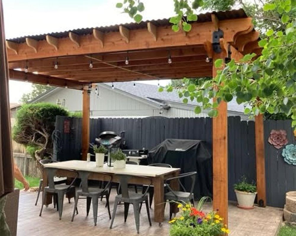 A wooden pergola with a table and chairs underneath it.