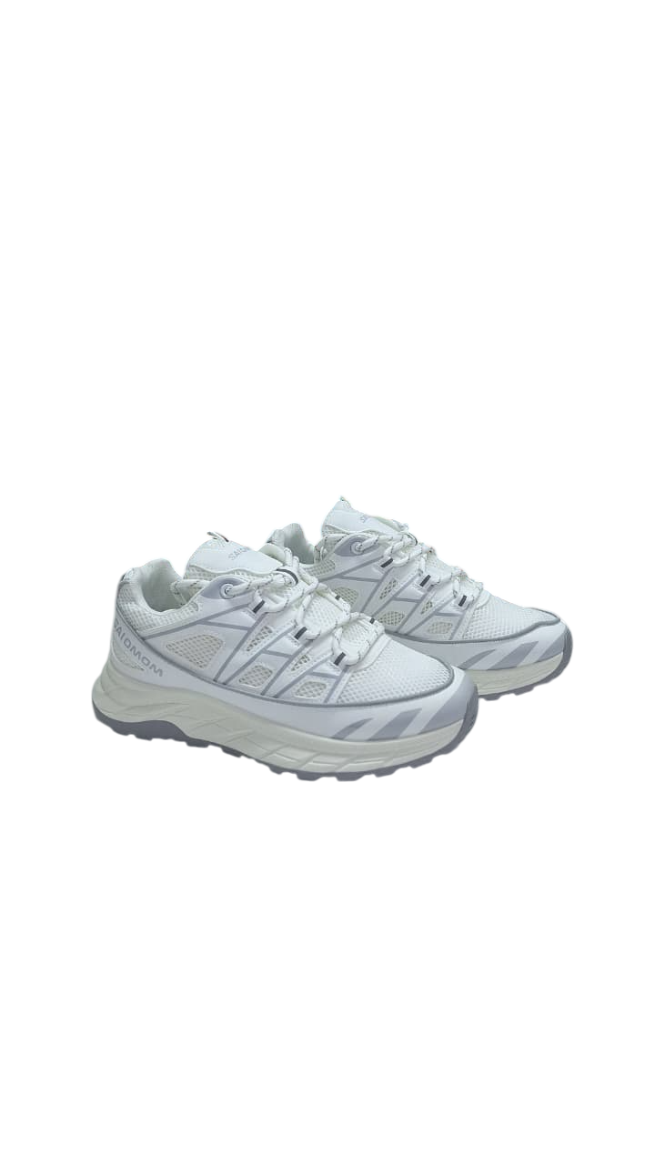 Zapatillas deportivas blancas con suela gris, cordones y detalles de malla.