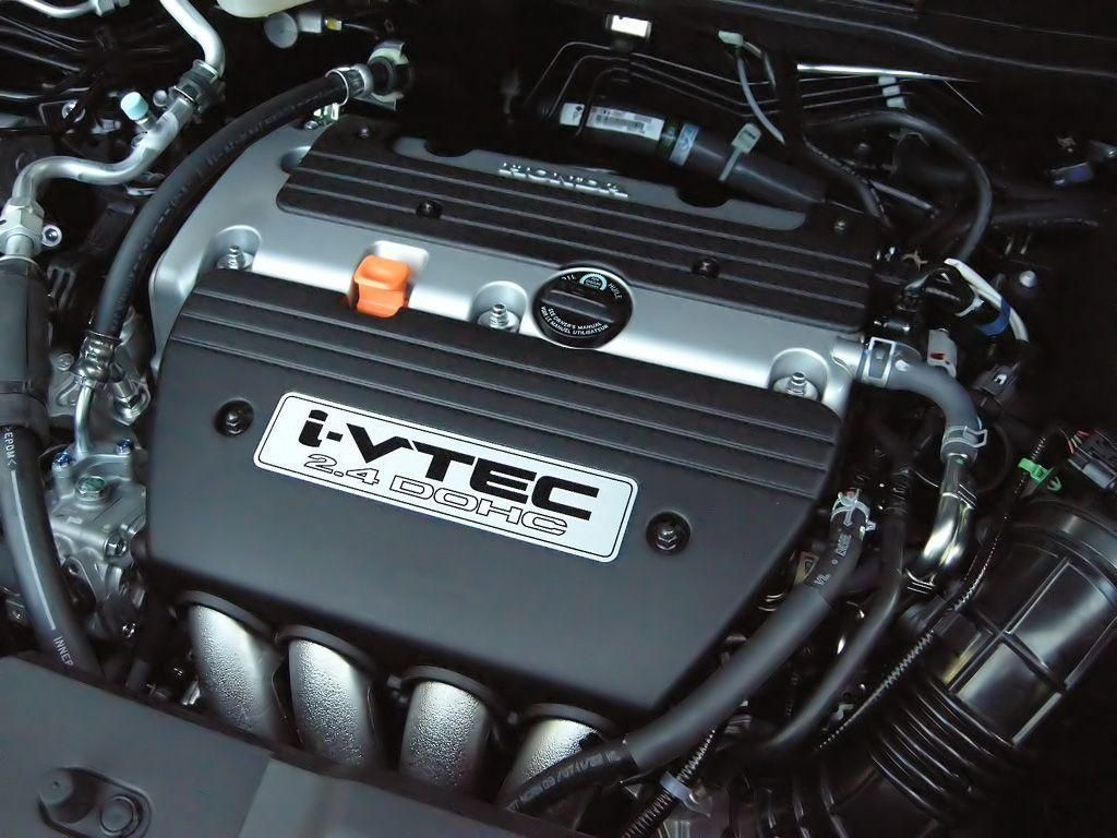 Close-up of a Honda i-VTEC engine, with black cover, silver accents, and various tubes and components.