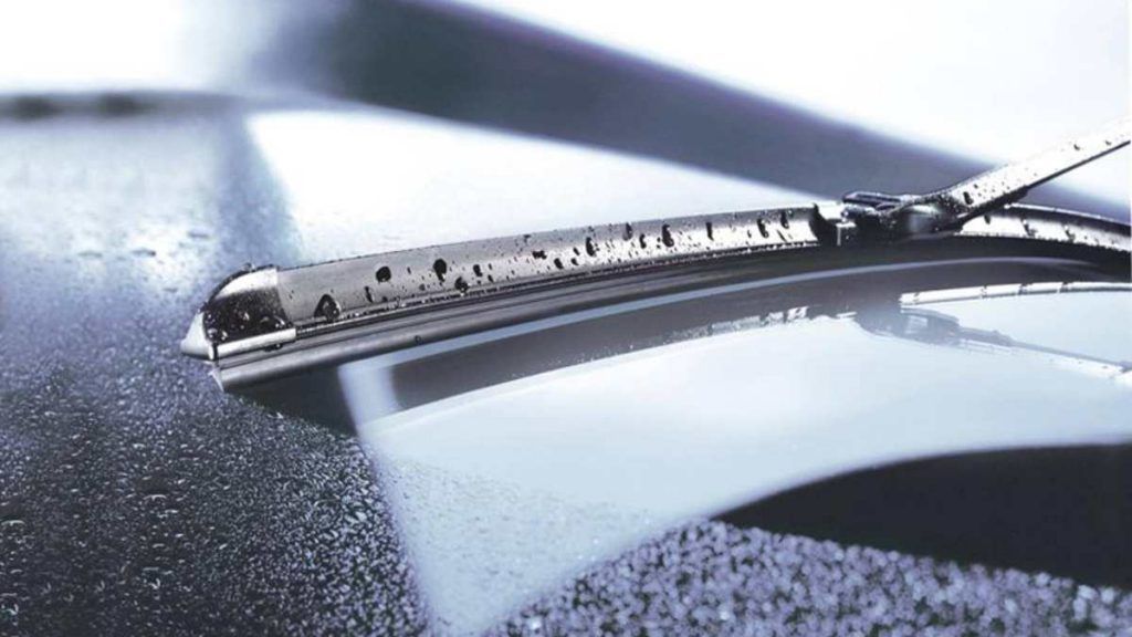 Windshield wiper clearing water droplets from a car's glossy surface.