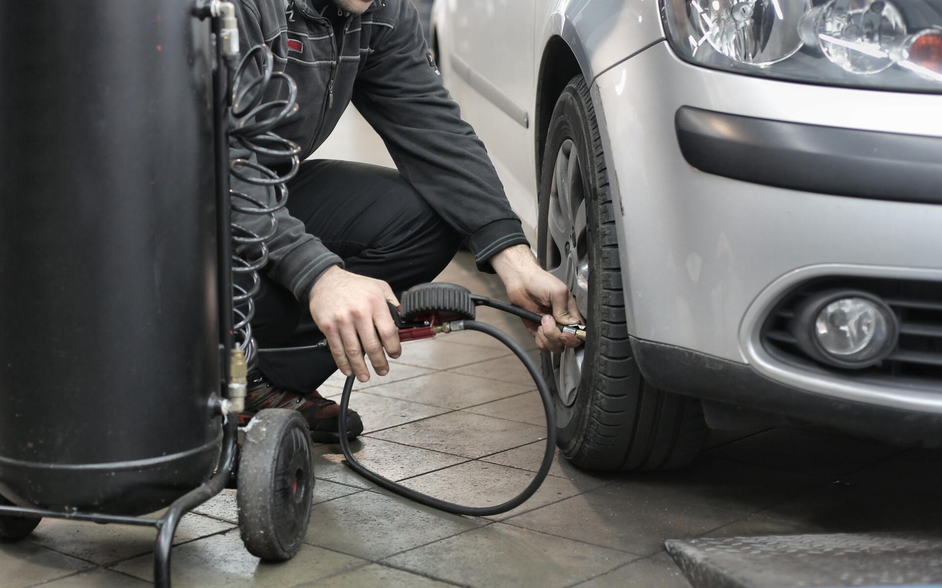 A man is pumping air into a car tire.