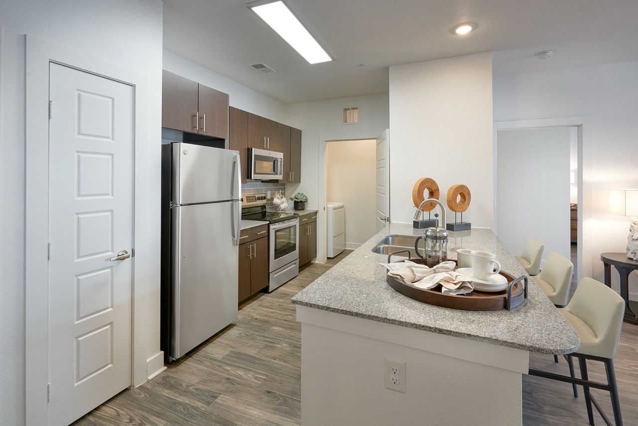 Modern apartment kitchen with stainless steel appliances, granite island, and seating.