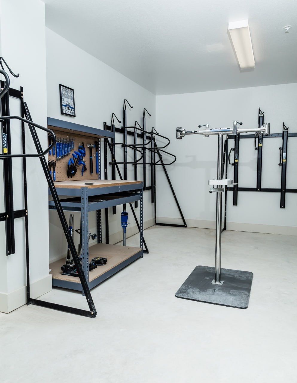 Well-lit community gym area with weight rack, bench, and wall-mounted tools.