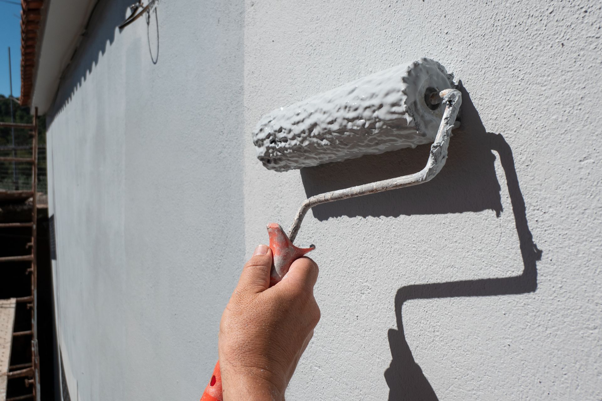 Hand painting a textured white wall with a paint roller.