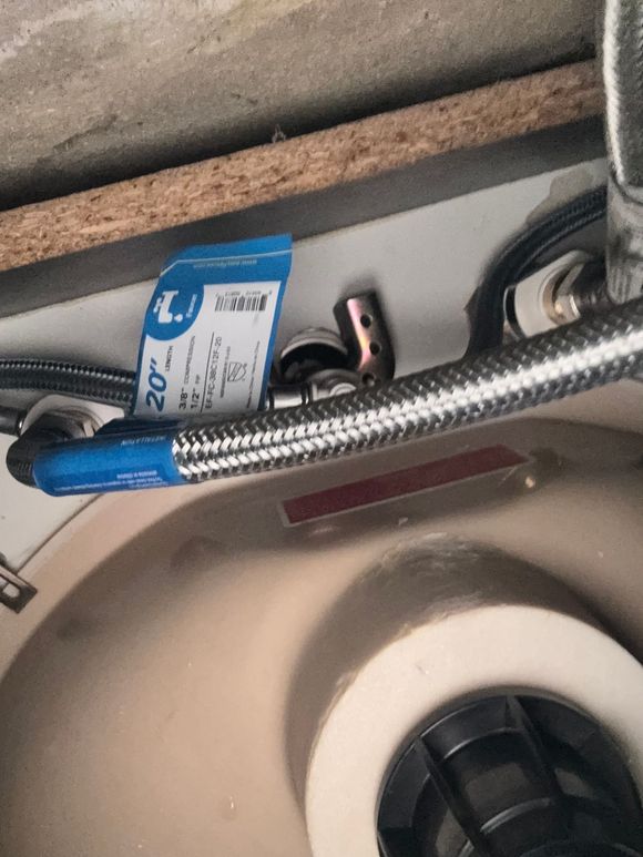 Water heater in a utility room with a pressure tank, various tools, and a red bucket.