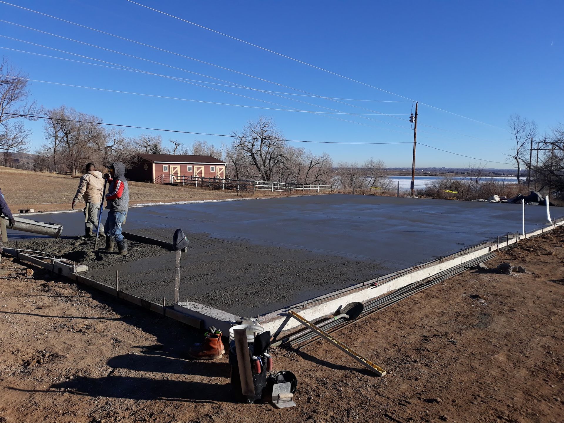 Concrete slab being poured by construction workers; outdoors, clear day.