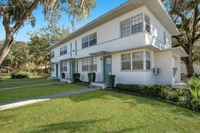 A white apartment building with blue doors and a lush green lawn.