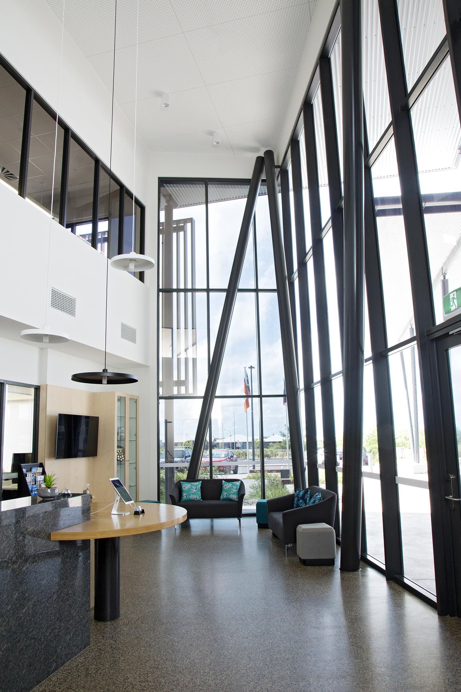 Modern hotel lobby with a granite reception desk, high ceilings, large windows, and contemporary lounge seating.