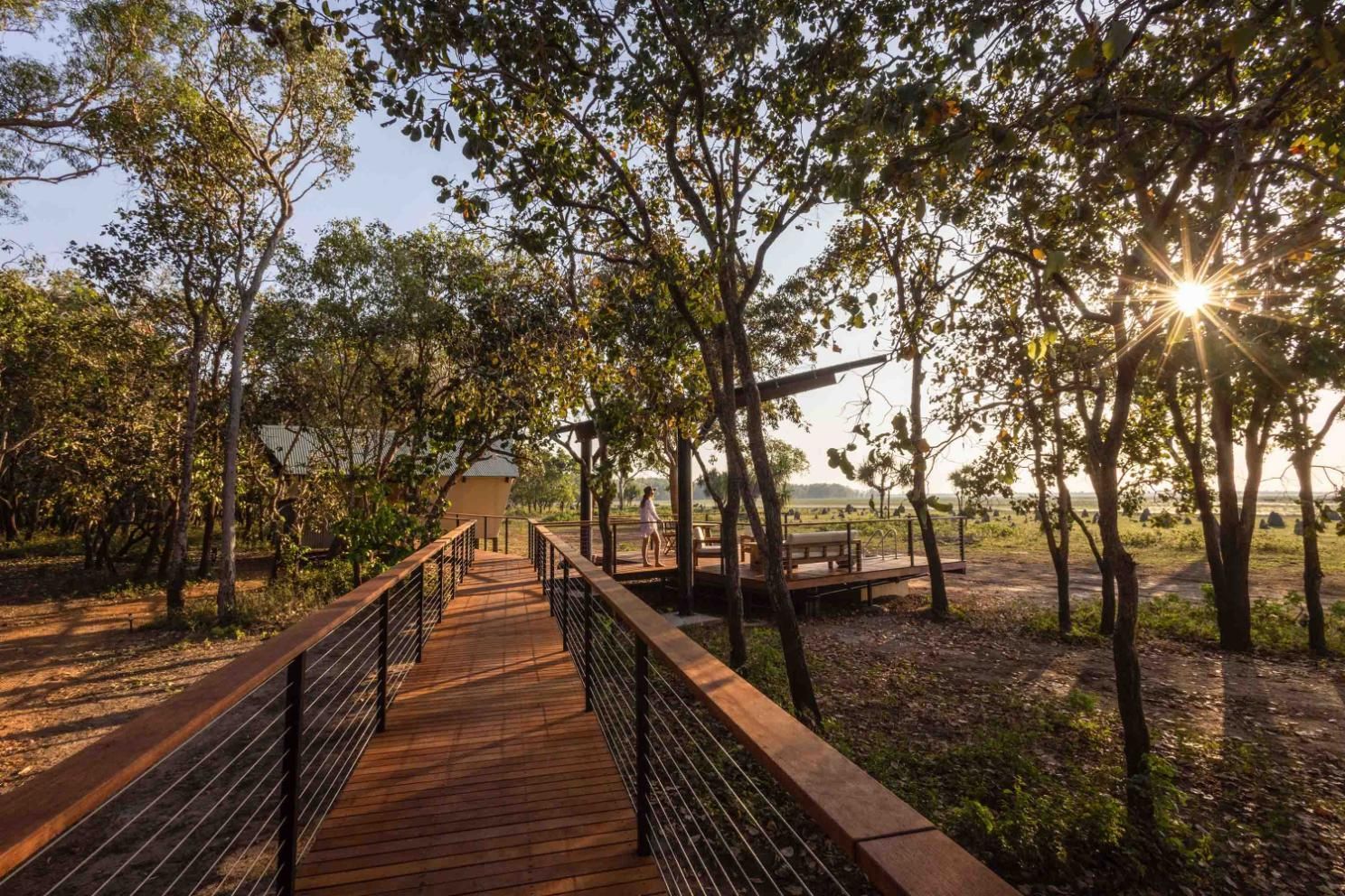 A white building with wooden privacy screens under a corrugated metal awning, surrounded by green shrubs.
