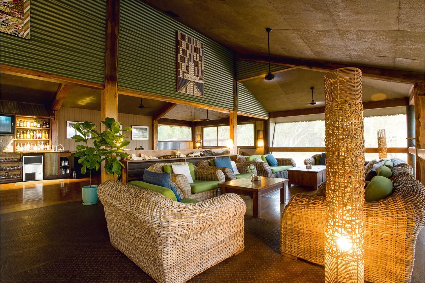 A white building with wooden privacy screens under a corrugated metal awning, surrounded by green shrubs.