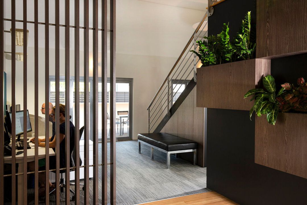 A bright, modern lobby with a curved reception desk, floor-to-ceiling windows, and contemporary lounge seating.