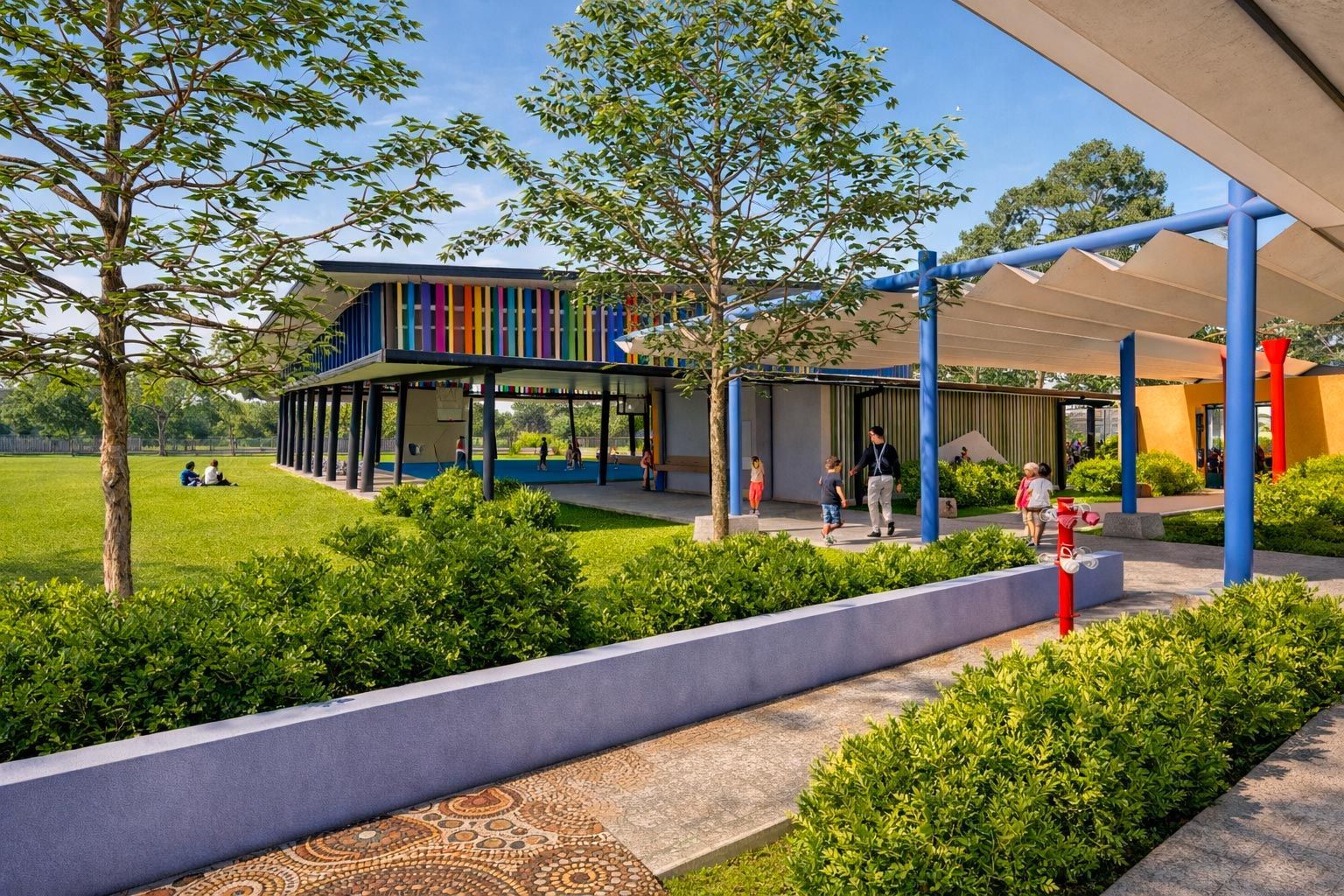 A vibrant, modern school building with a multicolored facade overlooks a sunny green lawn with a covered outdoor walkway.