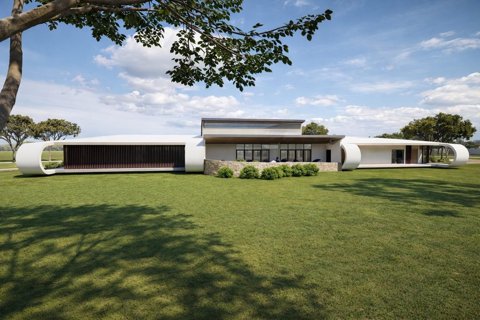 A long, modern white home with curved exterior walls and glass windows sits on a expansive, sunny green lawn.