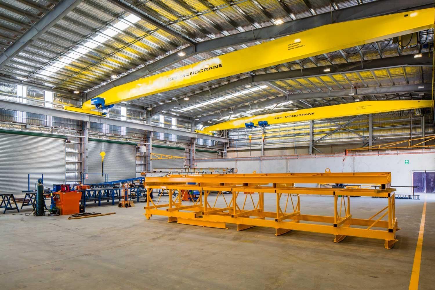 A white building with wooden privacy screens under a corrugated metal awning, surrounded by green shrubs.