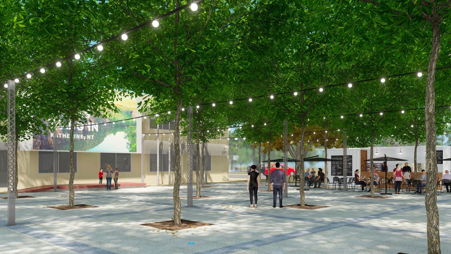 A public plaza with trees, cobblestone ground, string lights hanging above, and people sitting at outdoor tables.
