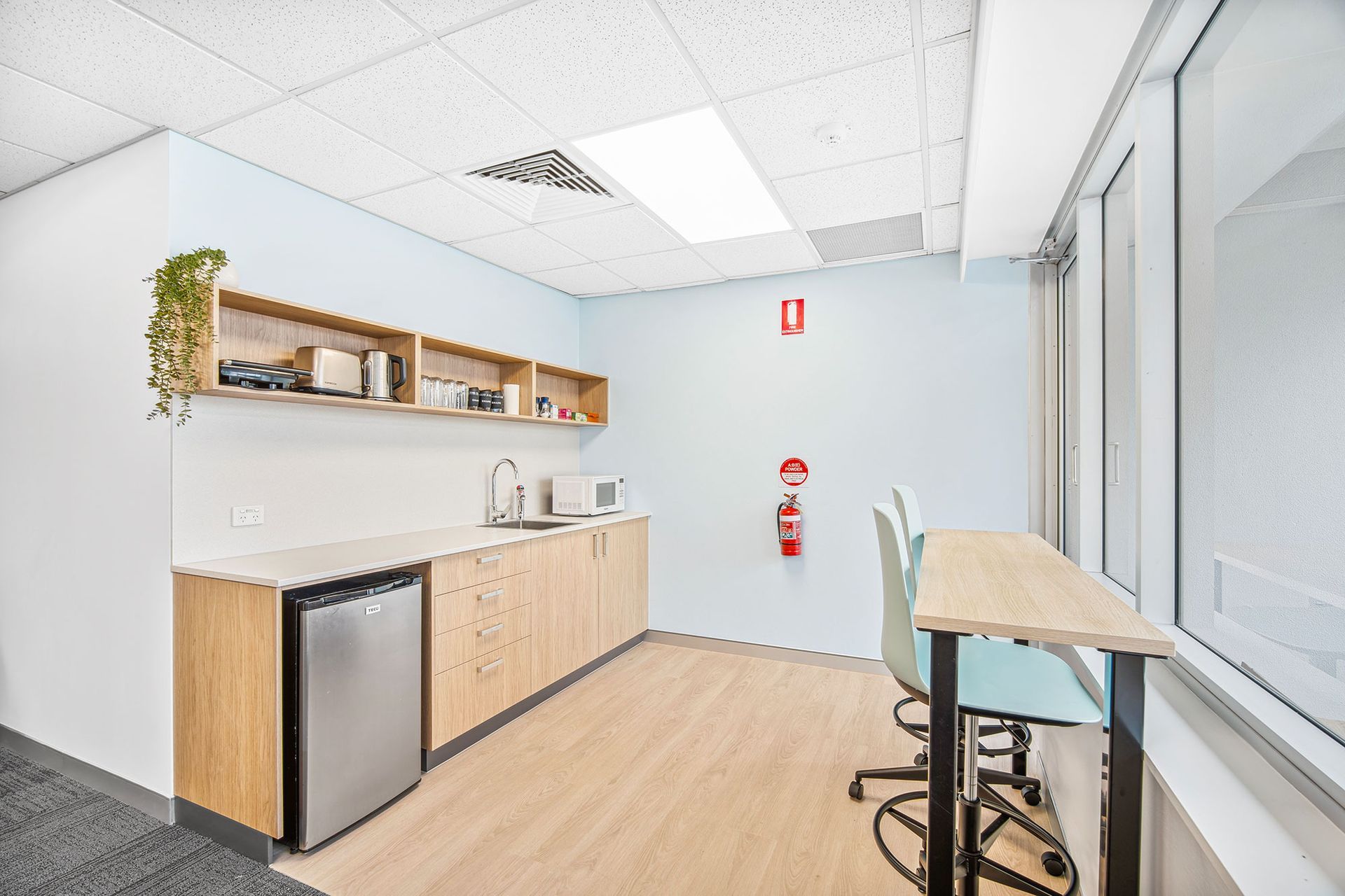 Modern, pink-themed hair salon interior with a central arched mirror, styling chairs, and shelving on wooden floors.