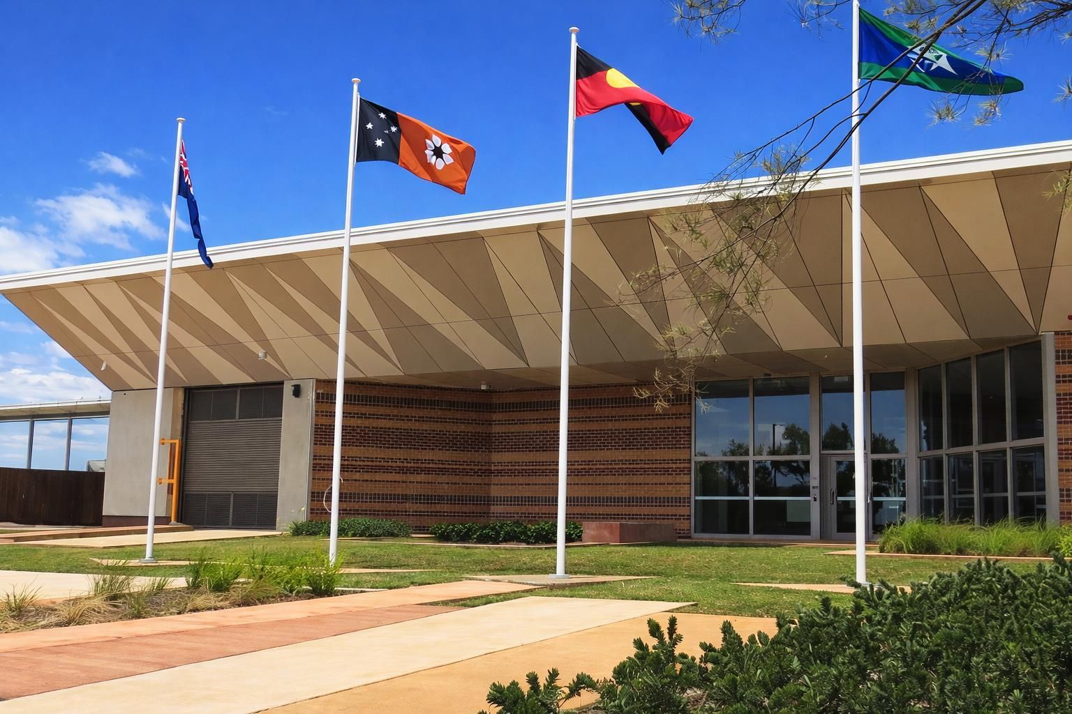 A bright, modern classroom with light wood floors, several small tables, area rugs, and a green accent wall.