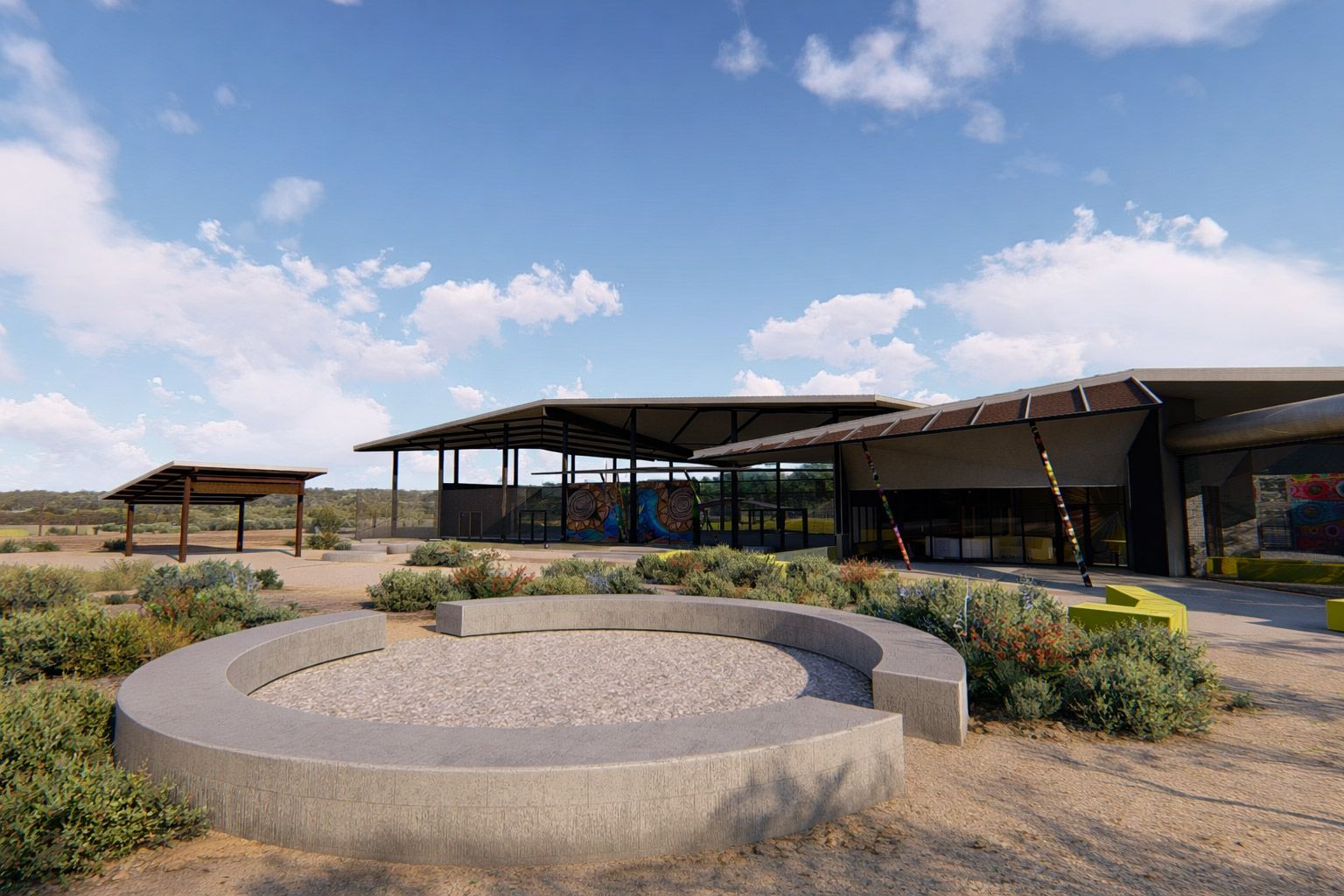 A modern, open-air building with a large roof sits in a desert landscape behind a circular stone seating area.