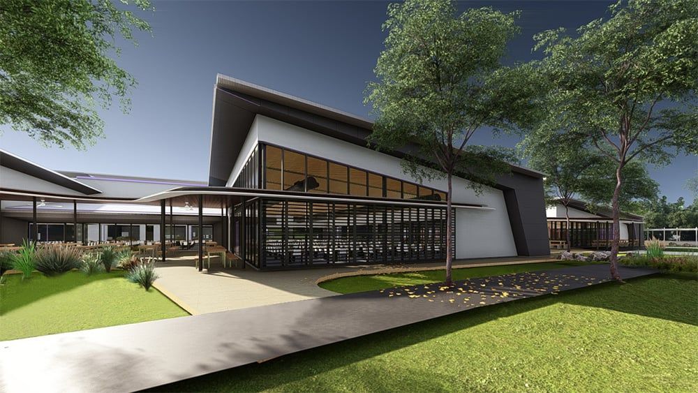 A modern, low-slung building with large glass windows and a slanted roof, set in a landscaped area with grass and trees.