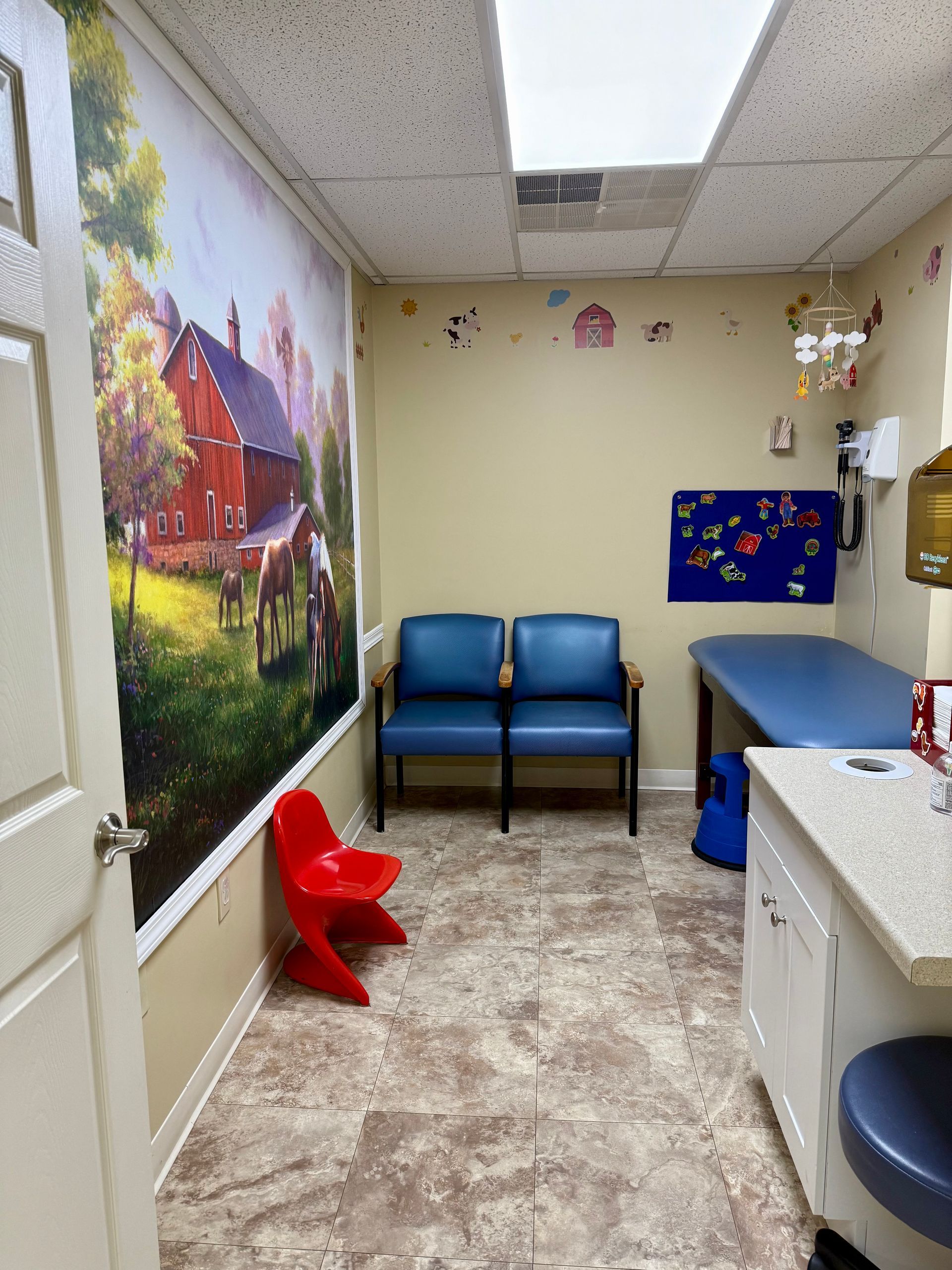 A waiting room with blue chairs and a red chair
