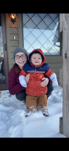 A woman wearing a cat in the hat is holding a baby.