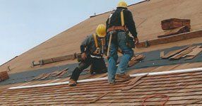 Two men are working on the roof of a building.