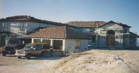 A truck is parked in front of a large house under construction.