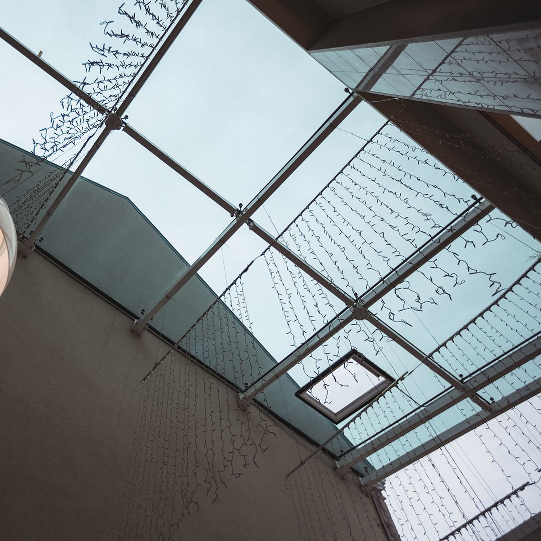 Angle-up view of a glass ceiling with spiderweb-like cracks and a skylight panel