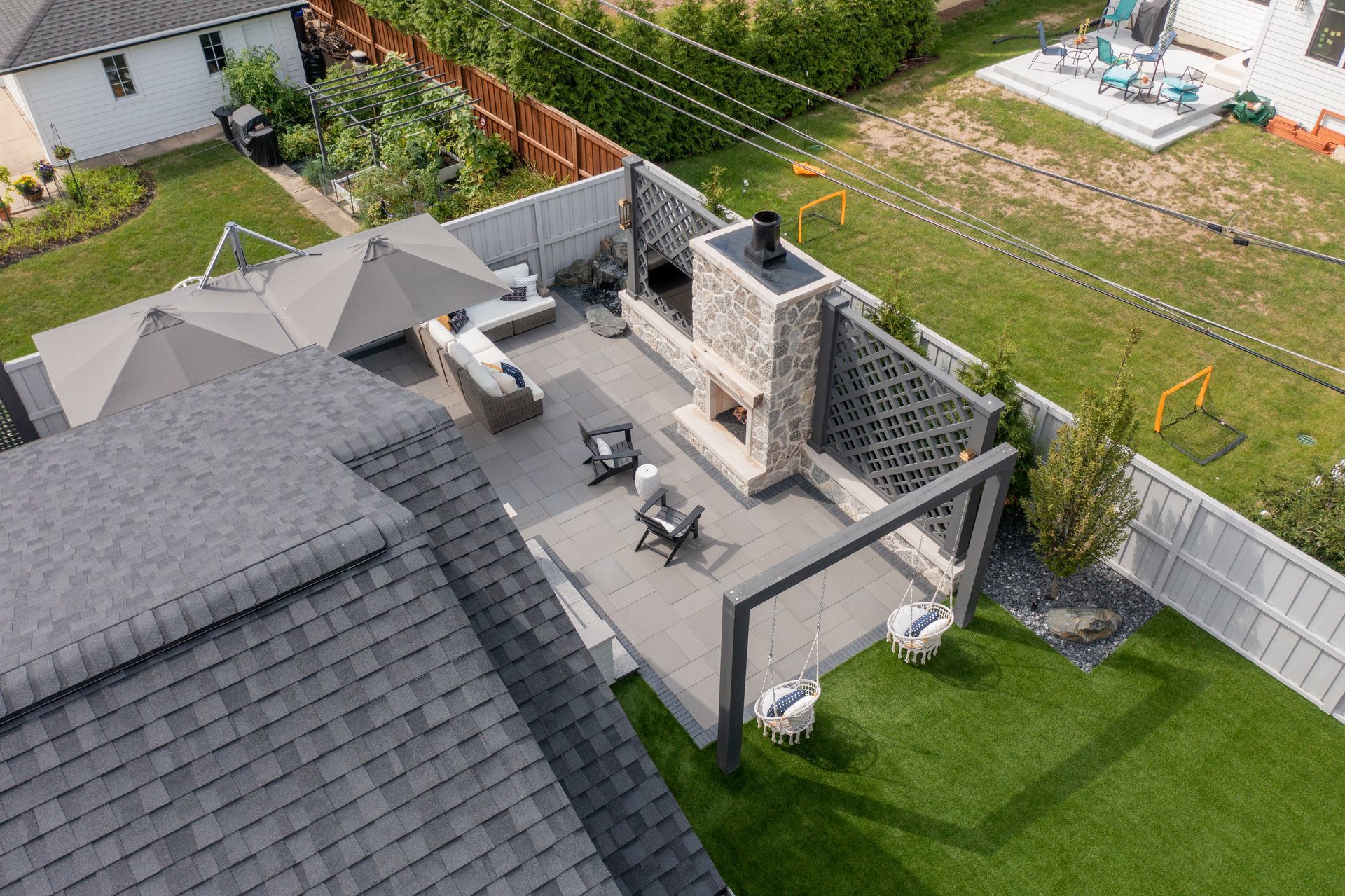 An aerial view of a backyard with a fireplace and umbrellas.