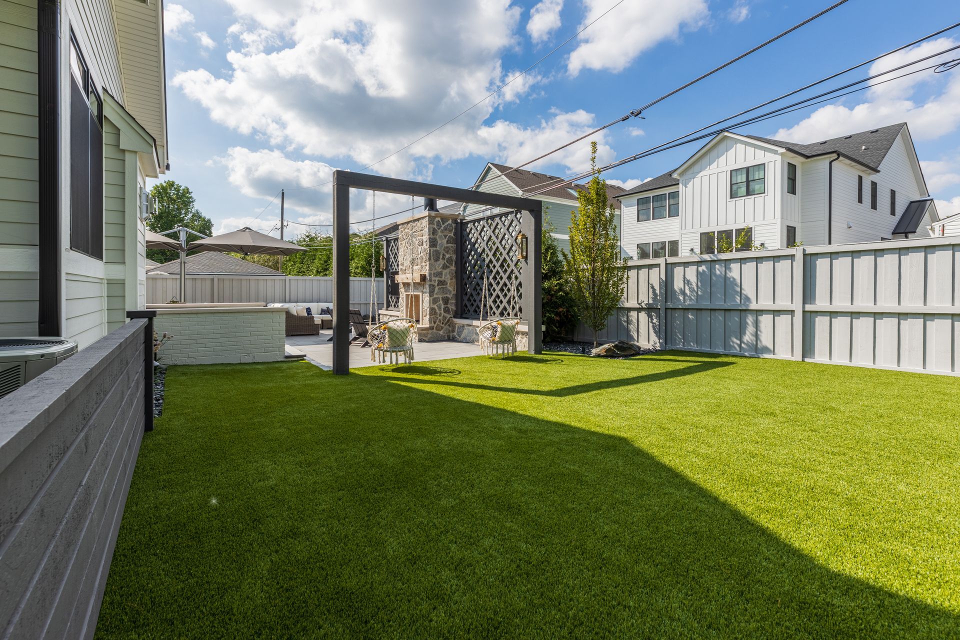 A backyard with a lush green lawn and a white fence.
