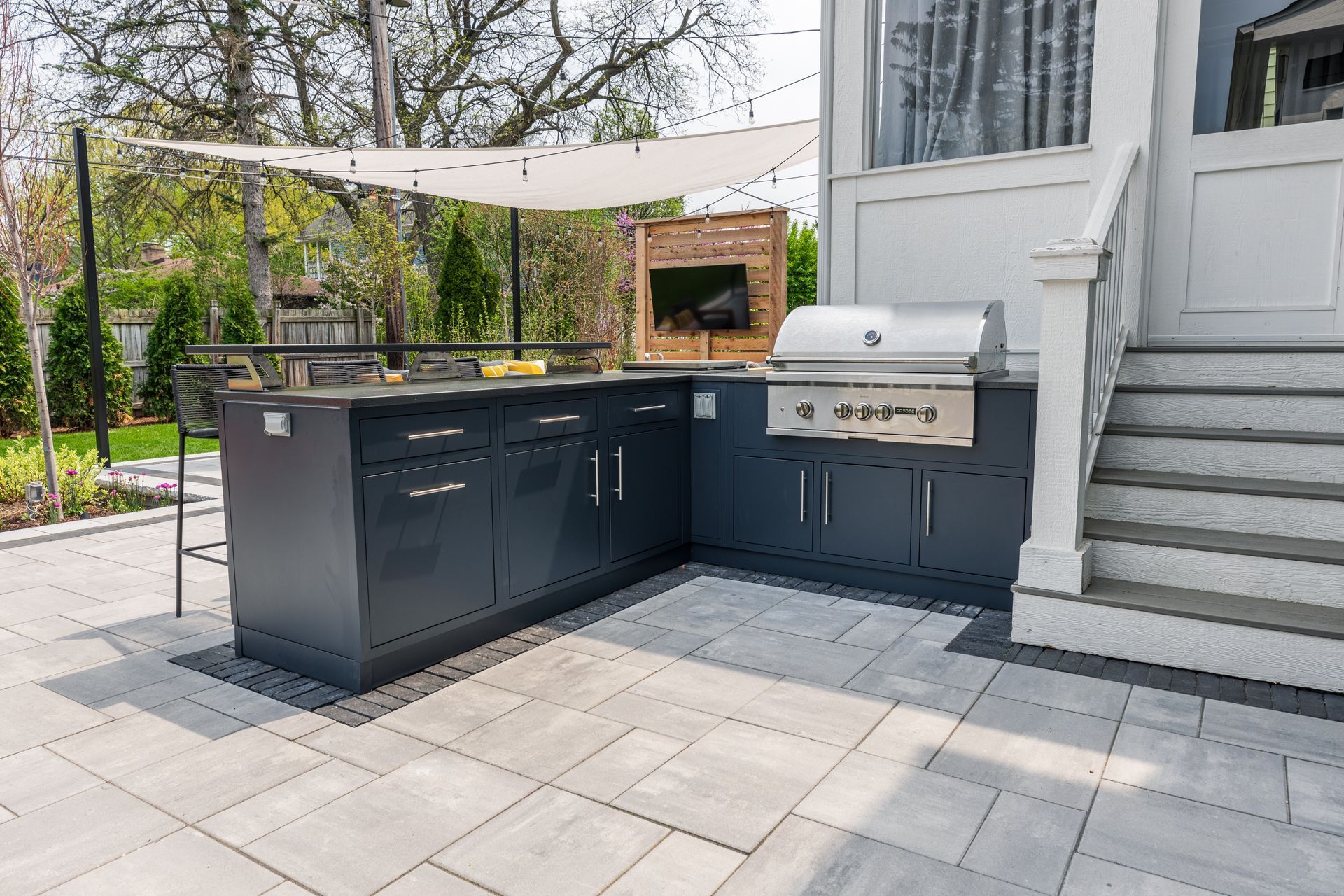 A large outdoor kitchen with a grill and stairs leading up to it.