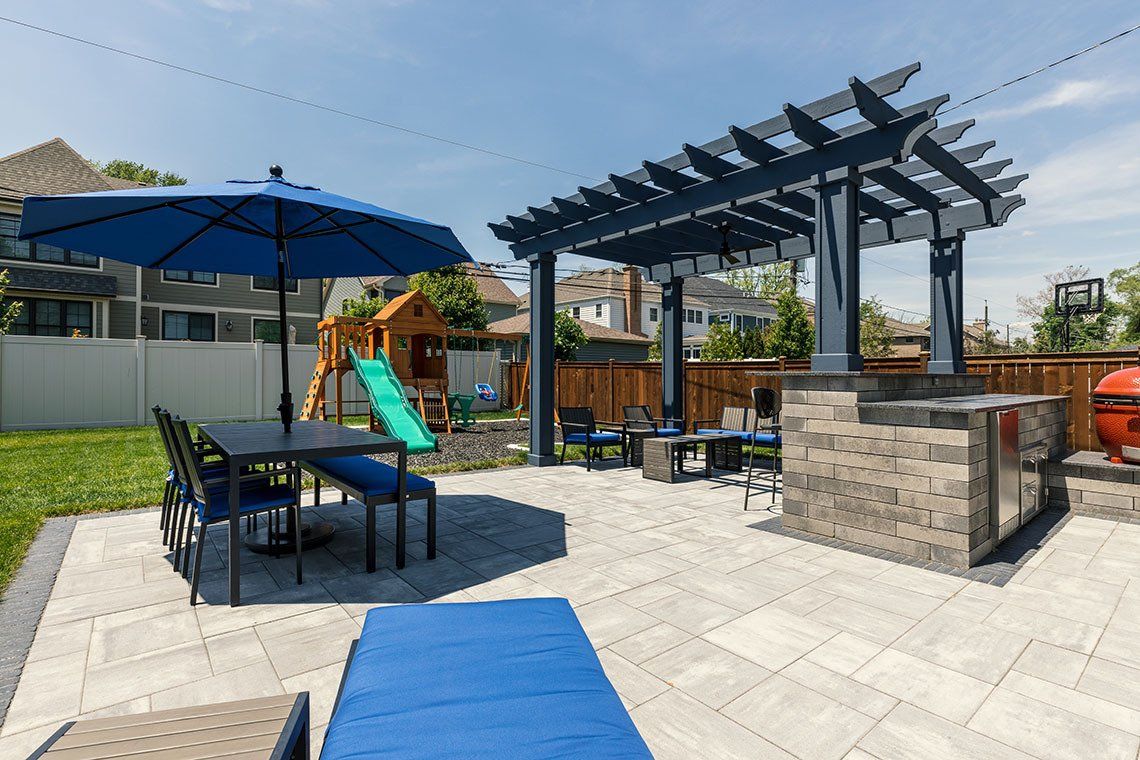 A patio with a table , chairs , umbrellas and a grill.