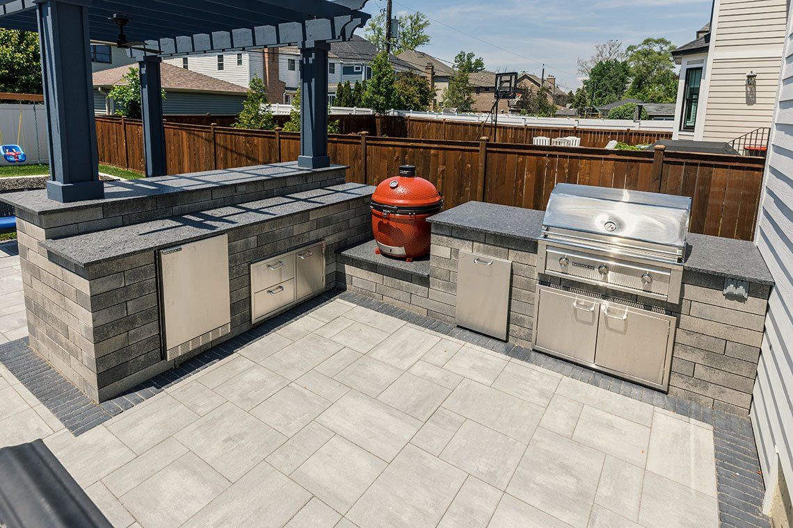 A large outdoor kitchen with a grill and a pergola.