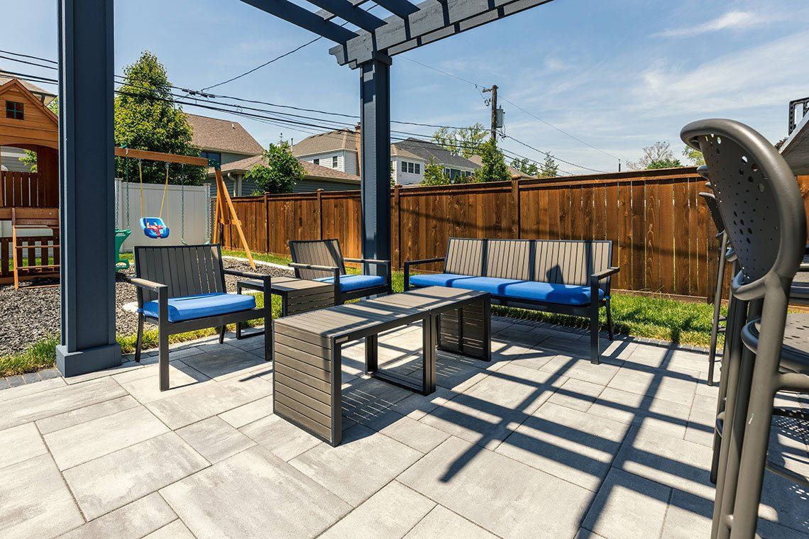 A patio with a pergola and patio furniture underneath it.