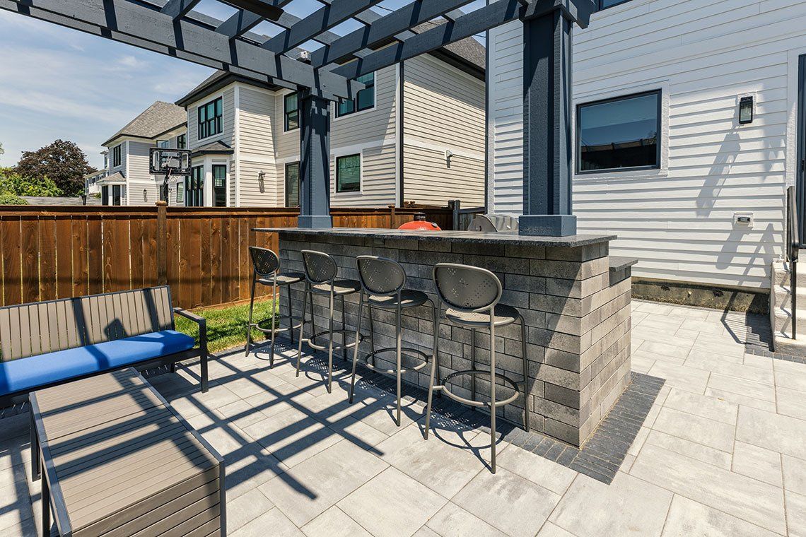 A patio with a bar and stools under a pergola.