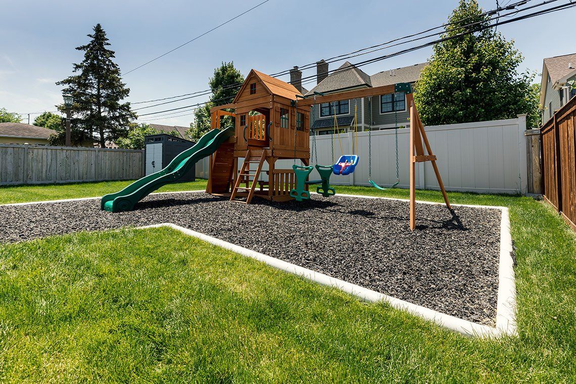 There is a playground in the backyard with a slide and swings.