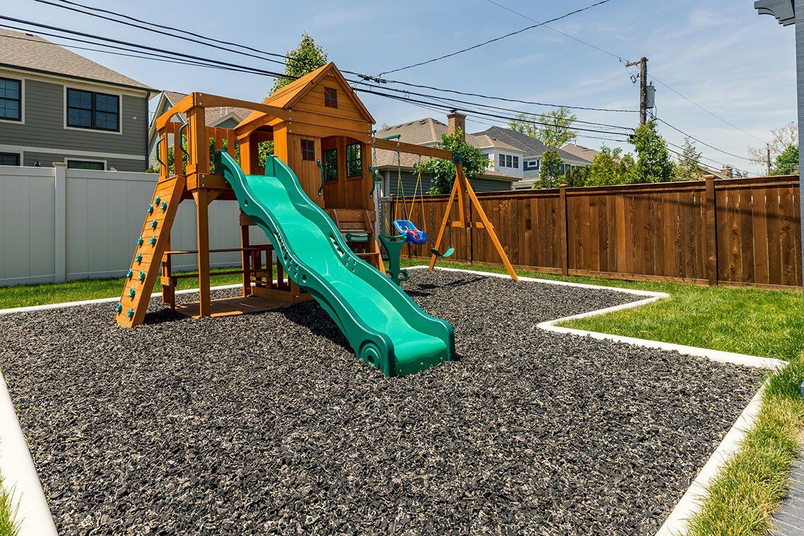 There is a playground with a slide and swings in the backyard.