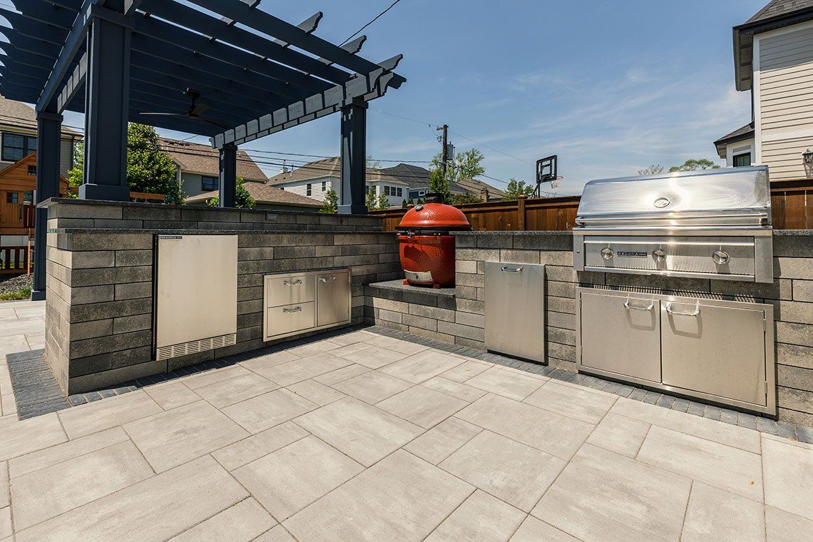 A large outdoor kitchen with a grill and a pergola.