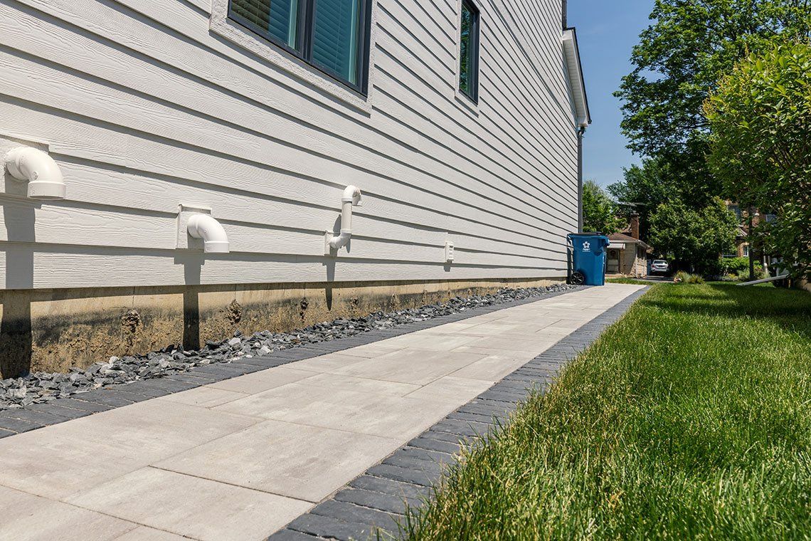 There is a sidewalk leading to the side of a house.