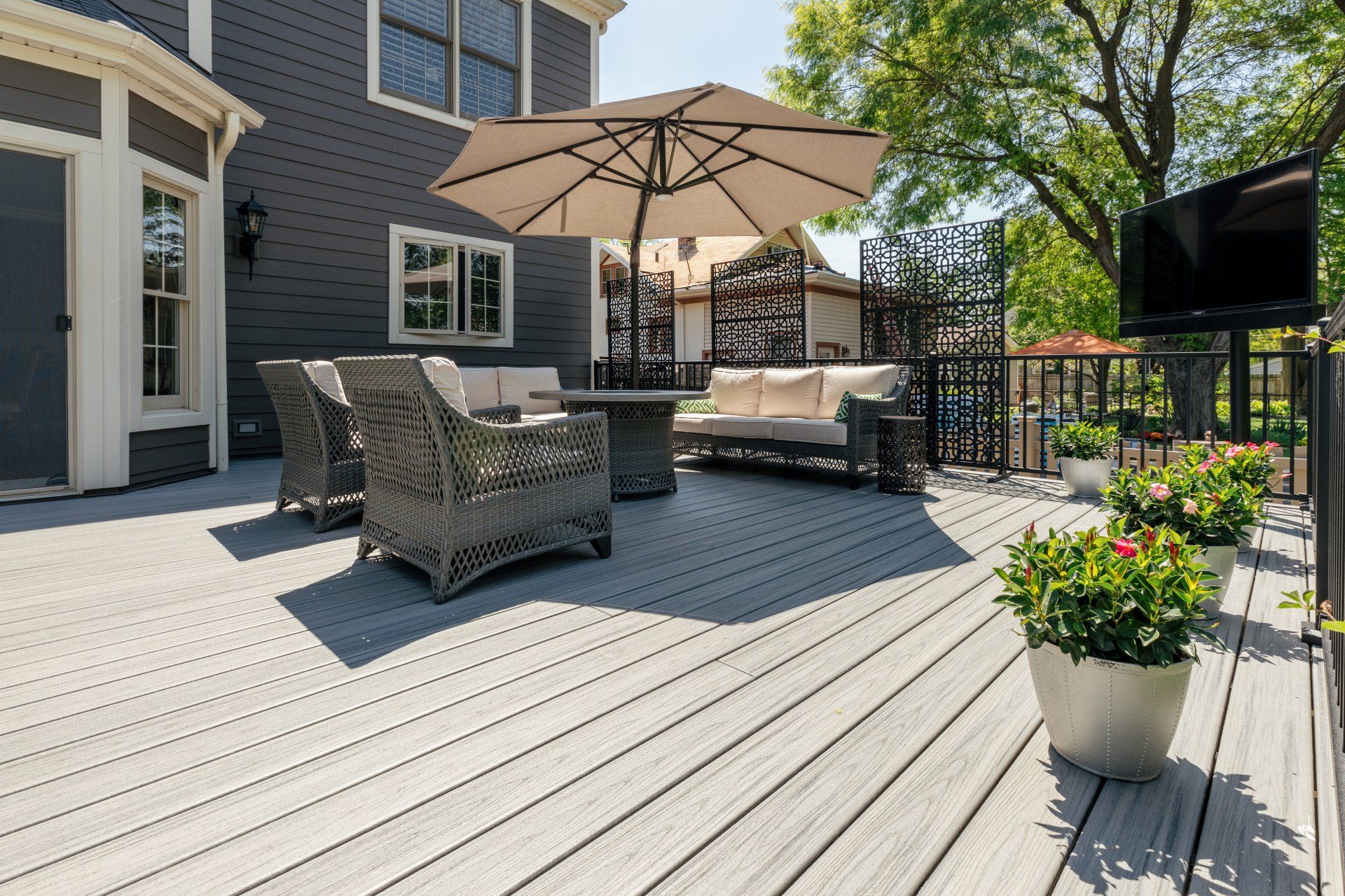 A deck with a couch , chairs , table and umbrella.