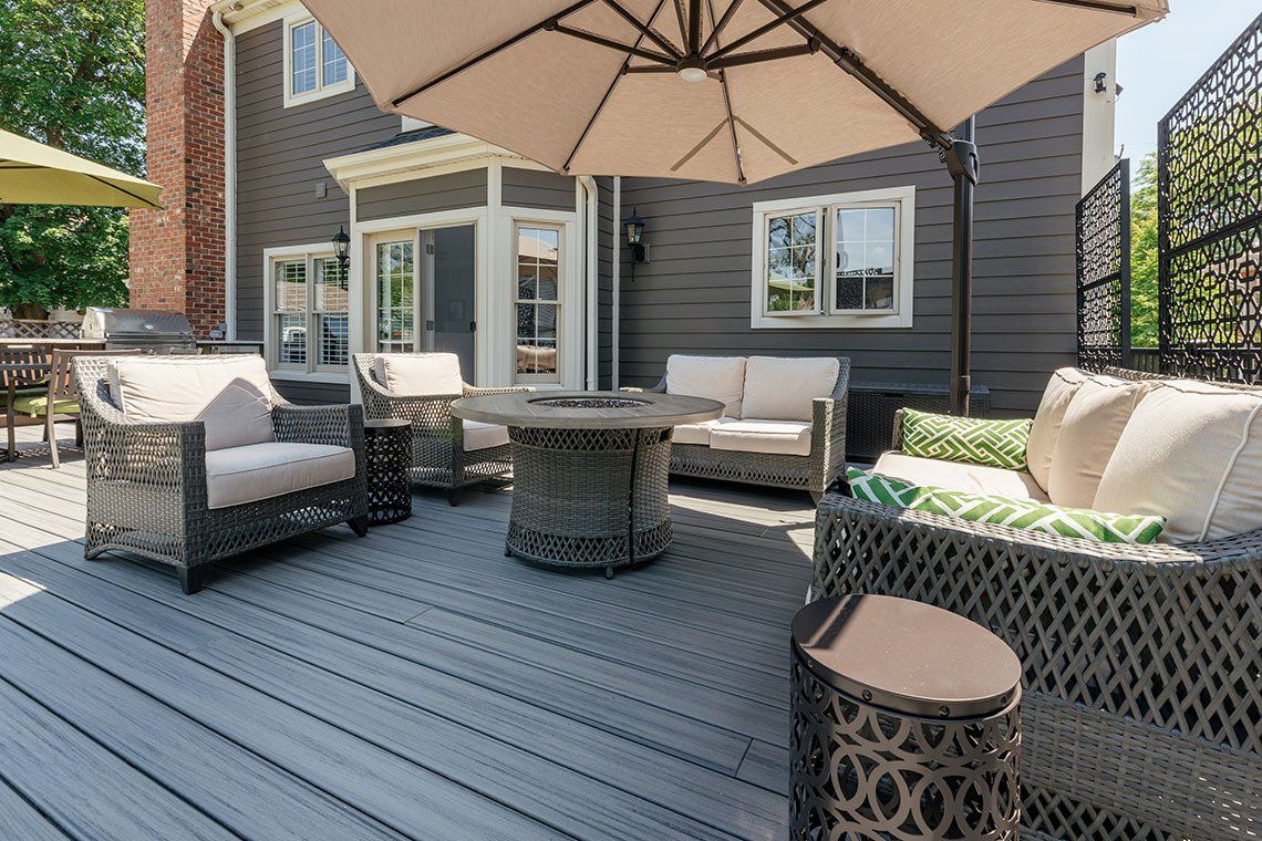 There is a large umbrella on the deck of a house.