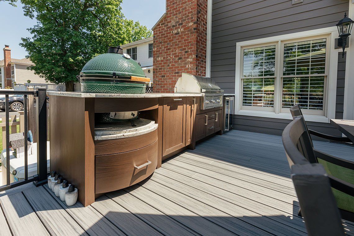 A large green egg is sitting on top of a wooden counter on a deck.