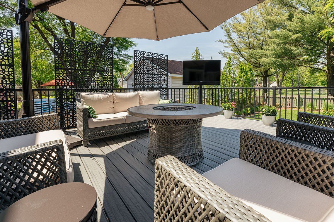 A deck with a couch , chairs , table and umbrella.