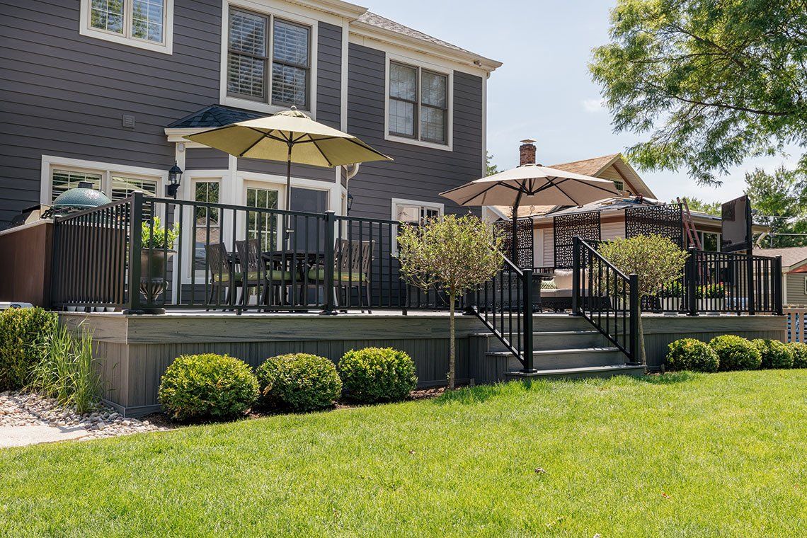 A large deck with umbrellas and chairs in front of a house.