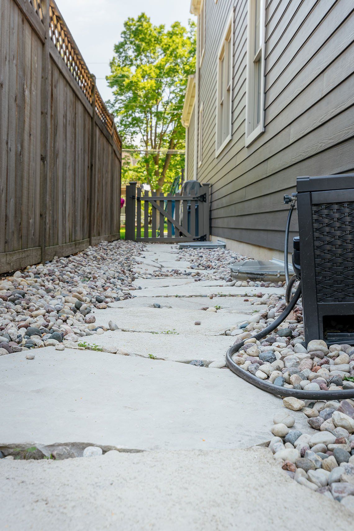 A stone walkway leading to a house with a wooden fence.