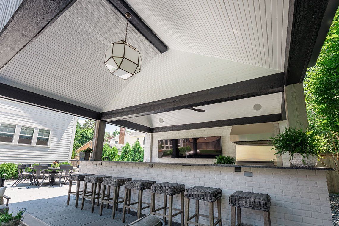 A covered patio with a bar and stools under a canopy.