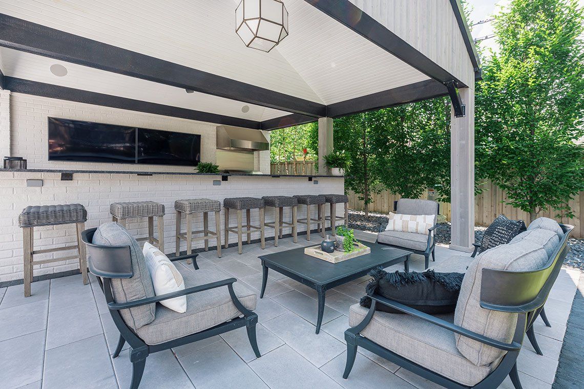 A patio with chairs , a table and a bar.