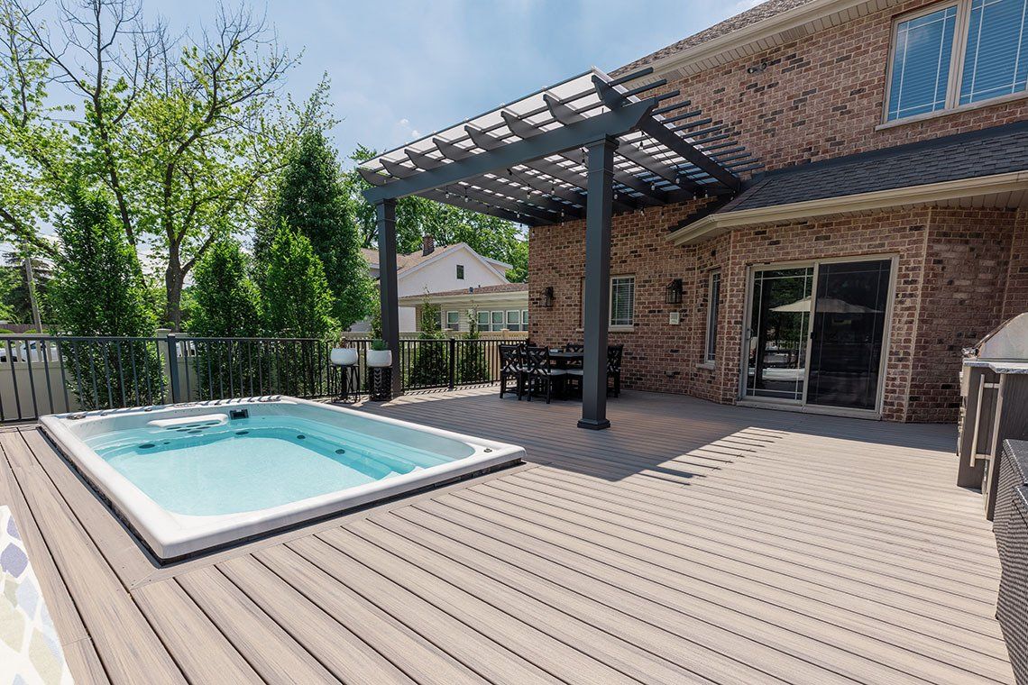 There is a hot tub on the deck of a house.