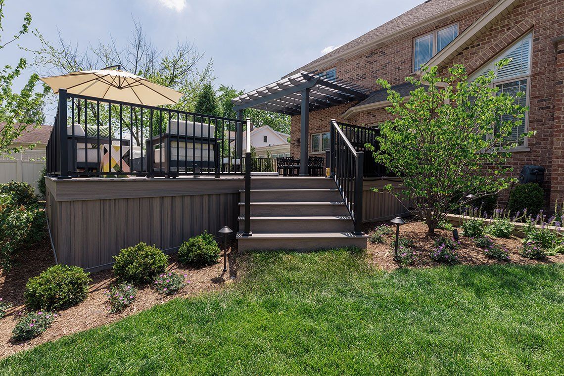 There is a deck with a pergola and stairs in the backyard of a house.